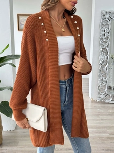 Detail of caramel knit cardigan featuring elegant white pearl embellishments on the collar