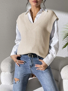 Detail of V-neck knitted sweater vest in beige featuring textured ribbing and layered style