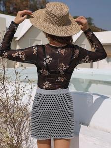 Back view of a sheer floral mesh long sleeve top and a crochet mini skirt set