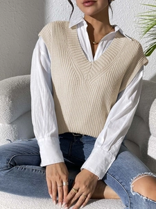 Detail of beige V-neck knitted vest with chunky texture layered over white shirt