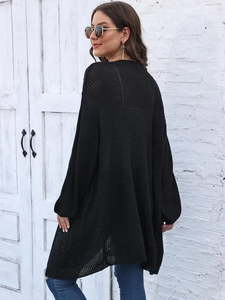 Close-up of black oversized knit cardigan featuring hollow mesh texture and chunky knit detail