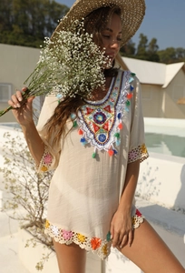 Détails de broderies géométriques colorées et de glands sur une robe de plage