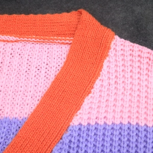 Detailed macro view of orange ribbed neckline and colorful chunky knit texture on cardigan