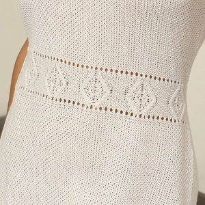 Detailed macro view of white knit mini dress featuring intricate hollow-out diamond patterns