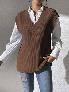Detail of dark brown cable-knit V-neck vest with side slits layered over a white shirt