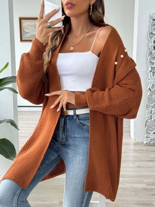 Detail of three white decorative pearls on the shoulder of a brown knit cardigan sweater
