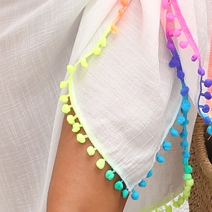 Détail d'un cache-maillot blanc avec pompons colorés et texture de tissu naturelle