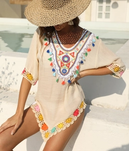 Détail du col en V avec broderie colorée et glands sur la robe de plage beige