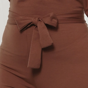 Detail of high-waist brown knitted jumpsuit showing a soft fabric texture and waist tie bow