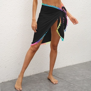 Détail de la jupe de plage noire à nouer avec des pompons multicolores et des franges
