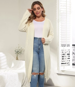 Detail of cream long knit cardigan styled with jeans in a bright minimalist setting