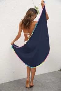 Détail du sarong de plage bleu marine avec bordure à pompons colorés et tissu léger