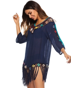 Detail of navy beach cover-up featuring colorful crochet floral trim and long fringe hem