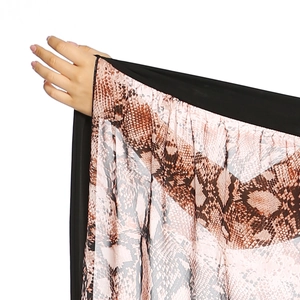 Dettaglio di tessuto in chiffon con stampa serpente e bordo nero per gonna da spiaggia