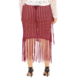 Detail of burgundy crochet beach skirt showing hollow mesh knit and long tassel fringe trim
