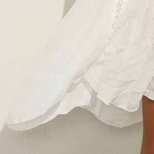 Detail of white textured fabric with delicate crochet lace edging on a summer dress