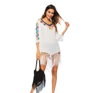 Detail of bohemian beach cover-up with colorful crochet neckline and long white tassels