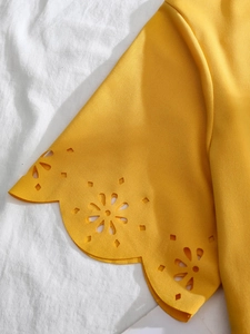 Detailed macro view of yellow scalloped cuff with intricate floral laser-cut patterns