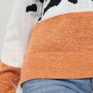 Dettaglio della trama del maglione in maglia con motivi bianchi e inserti arancioni