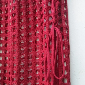 Detail of red hollow knit beach skirt with crochet pattern and side drawstring cord