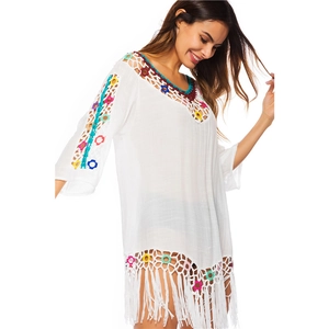 Detail of colorful crochet floral patterns and long tassels on white beach cover-up
