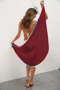 Détail d'un paréo de plage bordeaux avec pompons colorés et tissu léger transparent