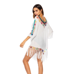 Detail of colorful hand-crocheted floral patterns and tassels on white beach cover-up