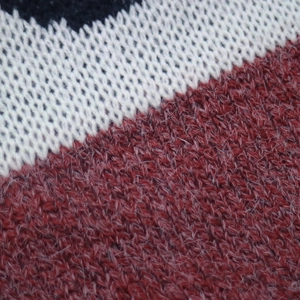 Dettaglio macro del tessuto a maglia tricolore con trame rosse, bianche e blu