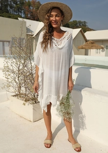 Dettaglio della trama all'uncinetto a V e volant sul copricostume bianco stile boho