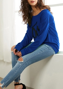 Detailansicht des königsblauen Sweatshirts mit schwarzem Grafikdruck und Denim-Hose