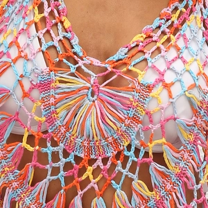 Gros plan détaillé sur les motifs au crochet multicolores et franges du paréo de plage