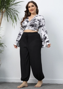 Detail view of tie-dye wrap top with V-neck and loose black drawstring lantern pants