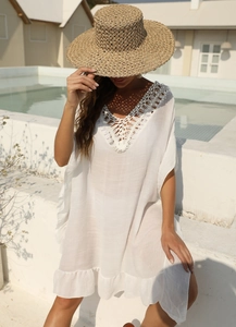 Dettaglio del vestito bianco da spiaggia con scollo a V e raffinata lavorazione all'uncinetto