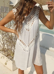 Detail of white bohemian crochet lace and fringe decoration on beach cover-up dress