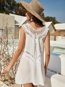 Close-up of white crochet beach cover-up featuring intricate V-neck fringe details