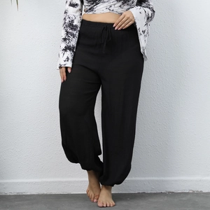Detail of loose black harem pants featuring high elastic waist with adjustable drawstring