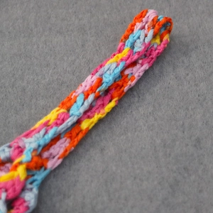 Vue détaillée des franges crochetées à la main en rose, bleu et jaune sur une robe de plage