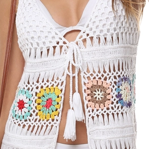 Détail du haut au crochet montrant des fleurs colorées, des lacets et des glands doux