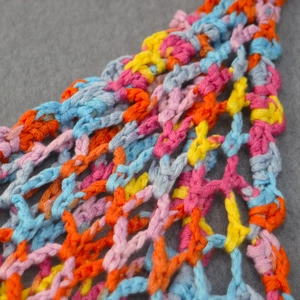 Détail de tissu en maille crocheté à la main avec fils de coton rose bleu et orange vibrants
