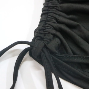 Detail of ruched side drawstring with precise stitching on black elastic fabric top