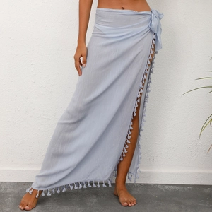 Detail of light blue wrap beach skirt with tassel trim and bohemian linen texture