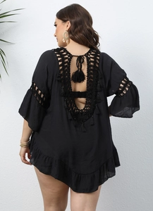 Detail view of black crochet beach cover-up featuring a V-shaped open back and fringe tassels
