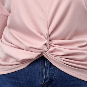 Detailed view of the twist knot hem and soft fabric texture on pink knit top