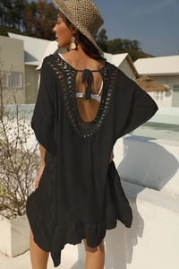Dettaglio macro dell'uncinetto sulla schiena nuda e volant sul vestito nero da mare
