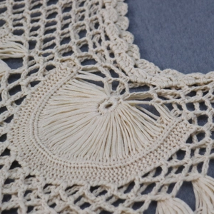 Gros plan détaillé du motif en maille crocheté main sur une robe de plage couleur crème