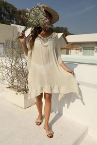 Dettaglio dello scollo a uncinetto boho su un abito da spiaggia beige con volant