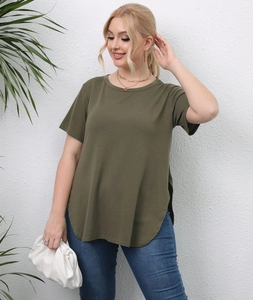 Detail view of side slit and curved hem on a loose olive green plus size T-shirt
