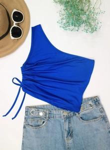 Flat lay of royal blue drawstring one-shoulder top with denim shorts and summer hat