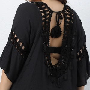 Detail of black crochet beach coverup with intricate hollow patterns and long tassels