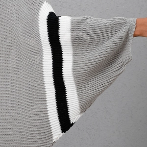 Detail view of knitted grey dress sleeve with batwing design and striped cuffs